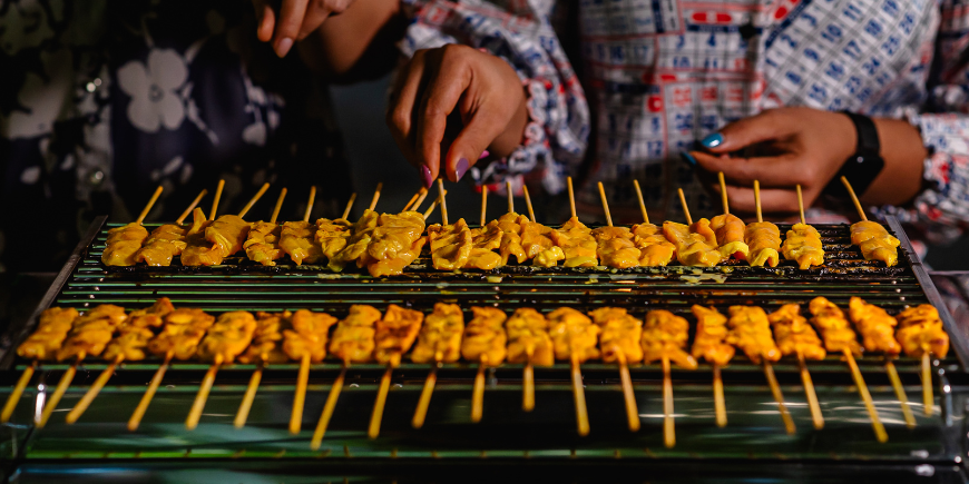 Kvinnor som lagar moo satay på grillen