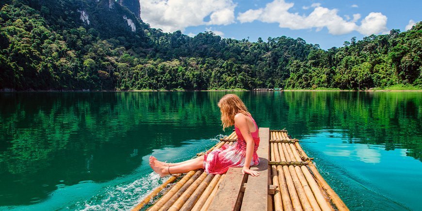 Ung flicka sitter vid sjön i Khao Sok National Park i Thailand