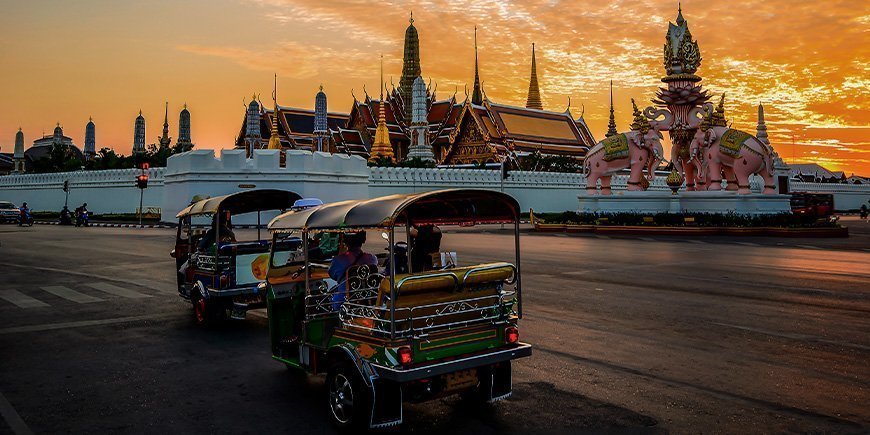 Tuk Tuk med utsikt över ett tempel i Bangkok