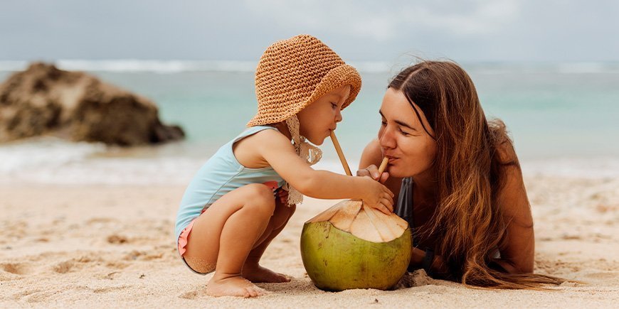 Ung kvinna och barn på en strand i Thailand