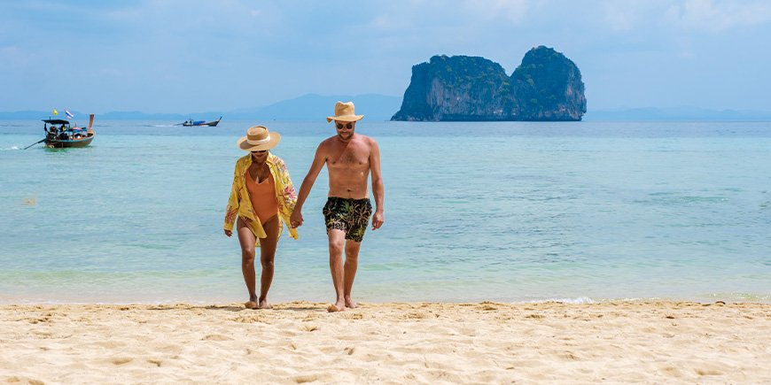 Par promenerar på stranden på ön Koh Ngai i Thailand