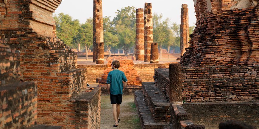 Man promenerar vid ruinerna i Sukhothai i soluppgången